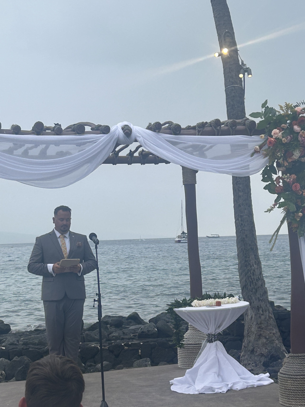 Peter officiating an oceanfront ceremony beneath a draped arch